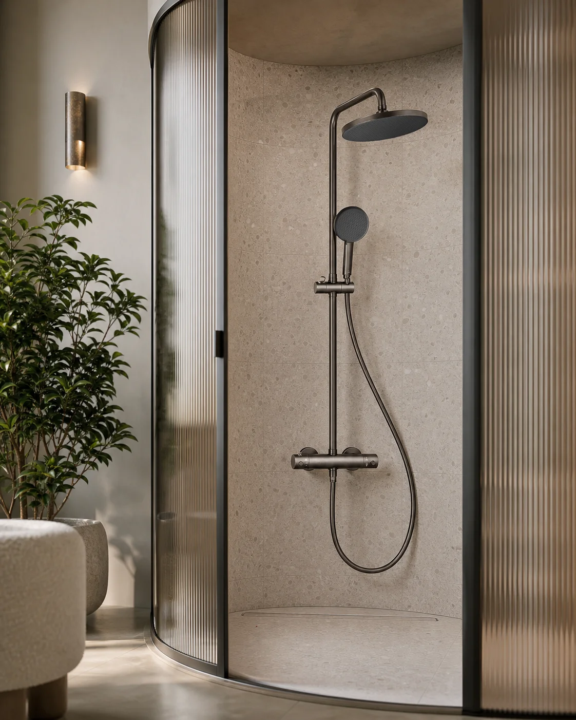 A NAIA shower column in gun grey inside a curved fluted-glass shower, beside a potted tree